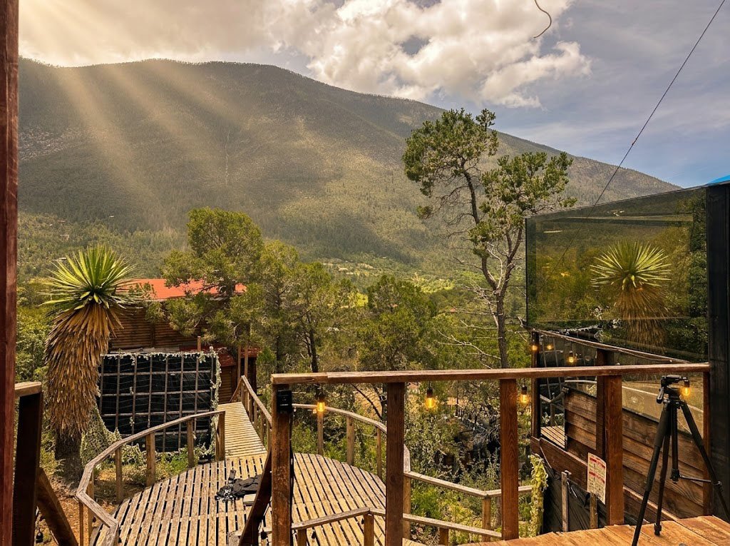 Terraza de SIRIUS al atardecer con luces cálidas, yucas y vista abierta a la montaña con rayos de sol filtrándose