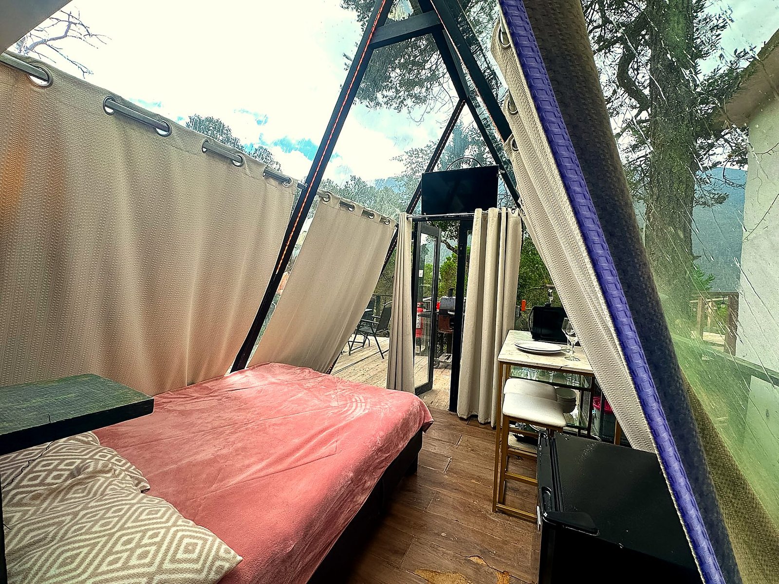 Interior de AURORA BOREAL con Smart TV, cocineta y salida directa a la terraza a través de los ventanales de cristal