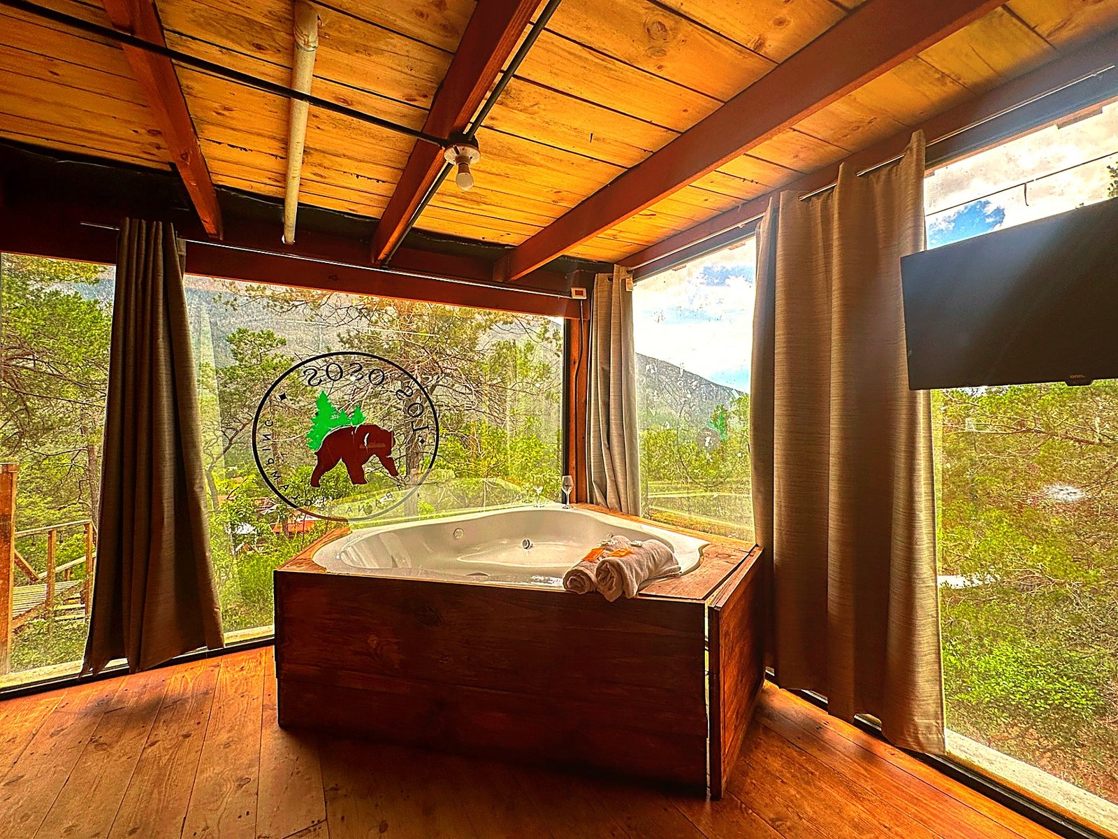 Jacuzzi privado de ATENEA rodeado de ventanales con vista panorámica a los pinos y la montaña