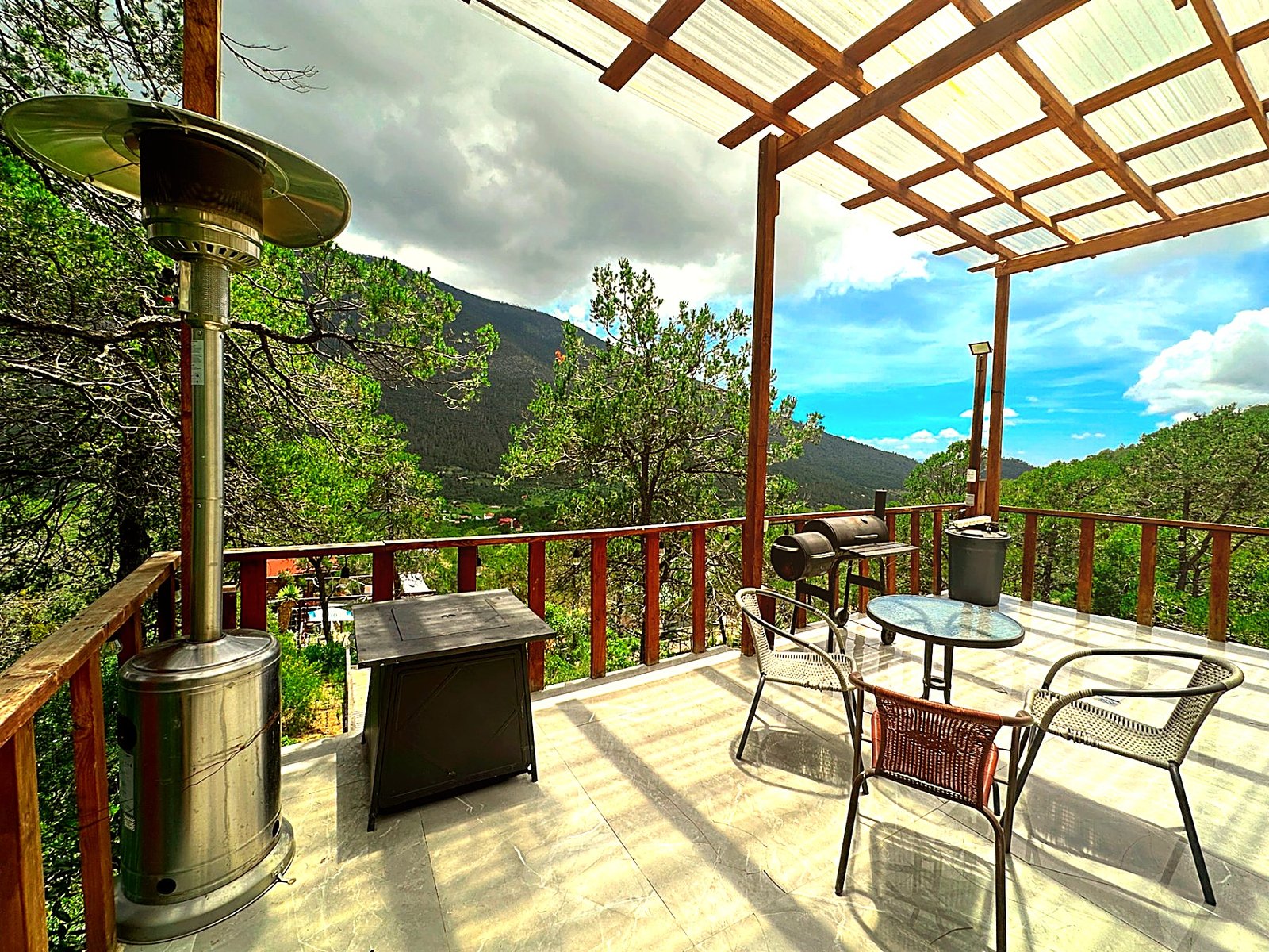 Terraza de ATENEA con calentador de patio, fogatero, asador y vista abierta al valle boscoso